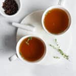Bone broth in mugs and garnished with fresh thyme