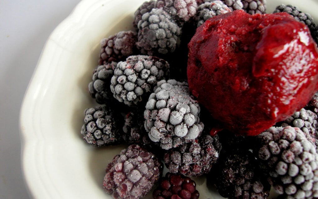 Blackberry sorbet over frozen blackberries on a white plate