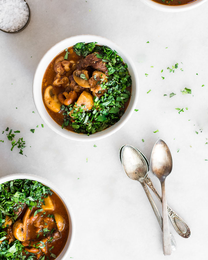 Mushroom stew in bowls garnished with chopped parsley and marjoram