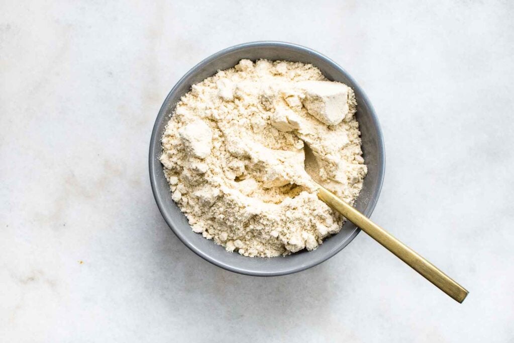 Coconut flour sits in a ceramic bowl on a marble surface.