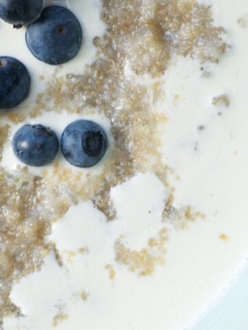 Closeup of porridge drizzled with cream and covered in blueberries