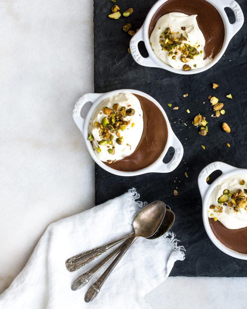 Chocolate Custard in ramekins, topped with whipped cream and chopped pistachios.