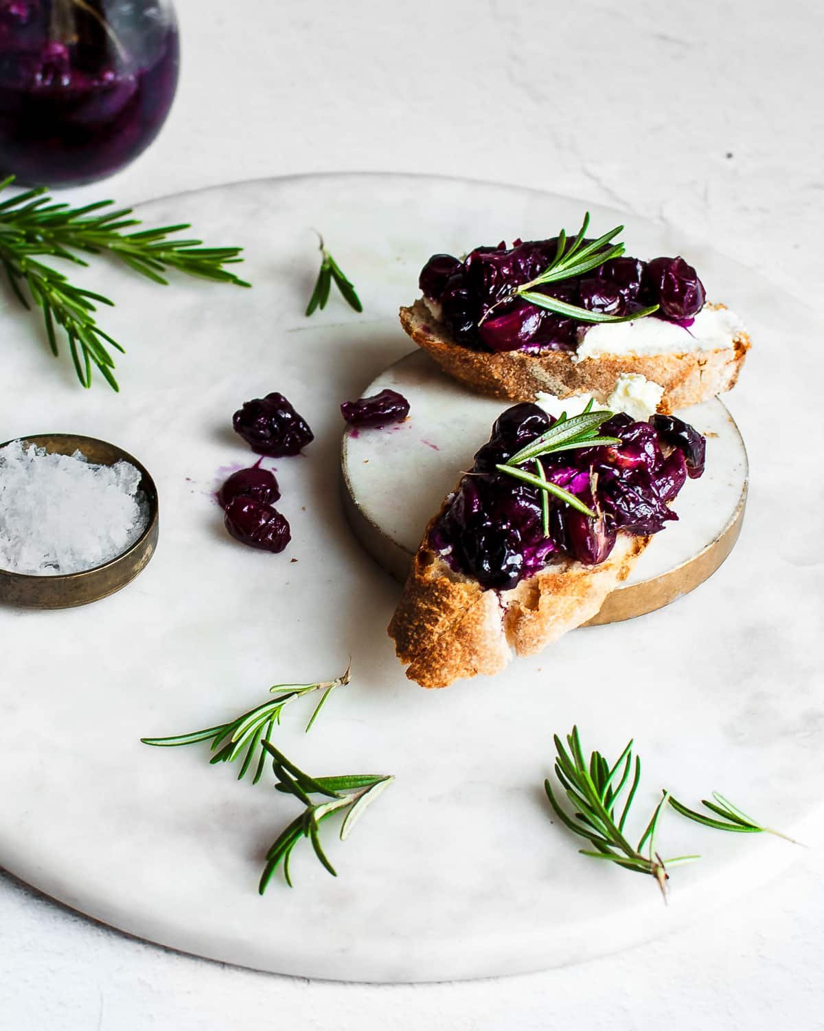 roasted grapes on a toasted baguette spread with cream cheese and garnished with rosemary