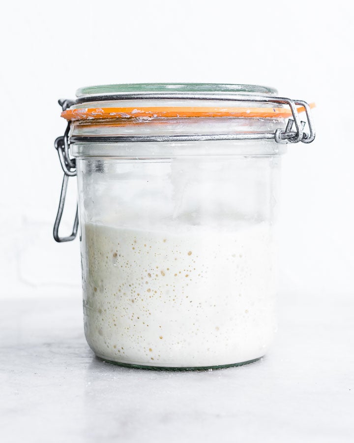 Bubbly sourdough starter in a glass jar.