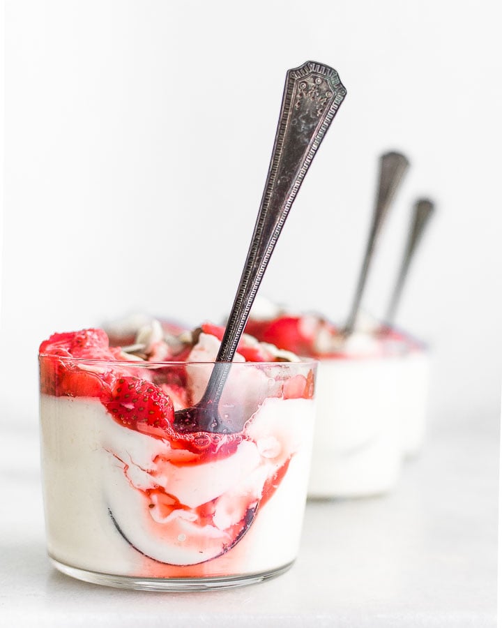 Three glasses filled with yogurt panna cotta and honey roasted strawberries.