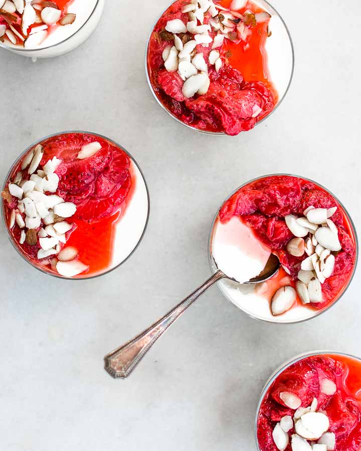 Yogurt panna cotta served with honey-roasted strawberries and slivered almonds.