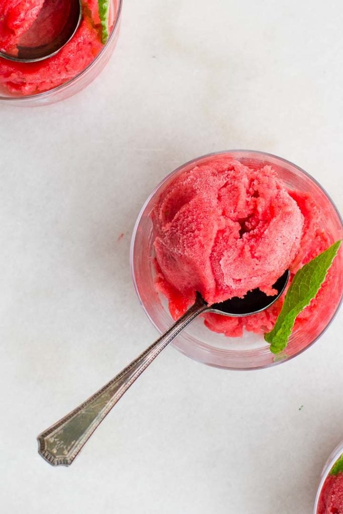 Strawberry Sorbet garnished with mint in glass bowls with silver spooons.