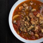 tomato based soup in a pot with mushrooms beans and lentils