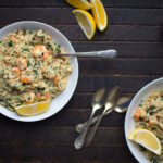 two dishes of shrimp risotto garnished with lemon and parsley
