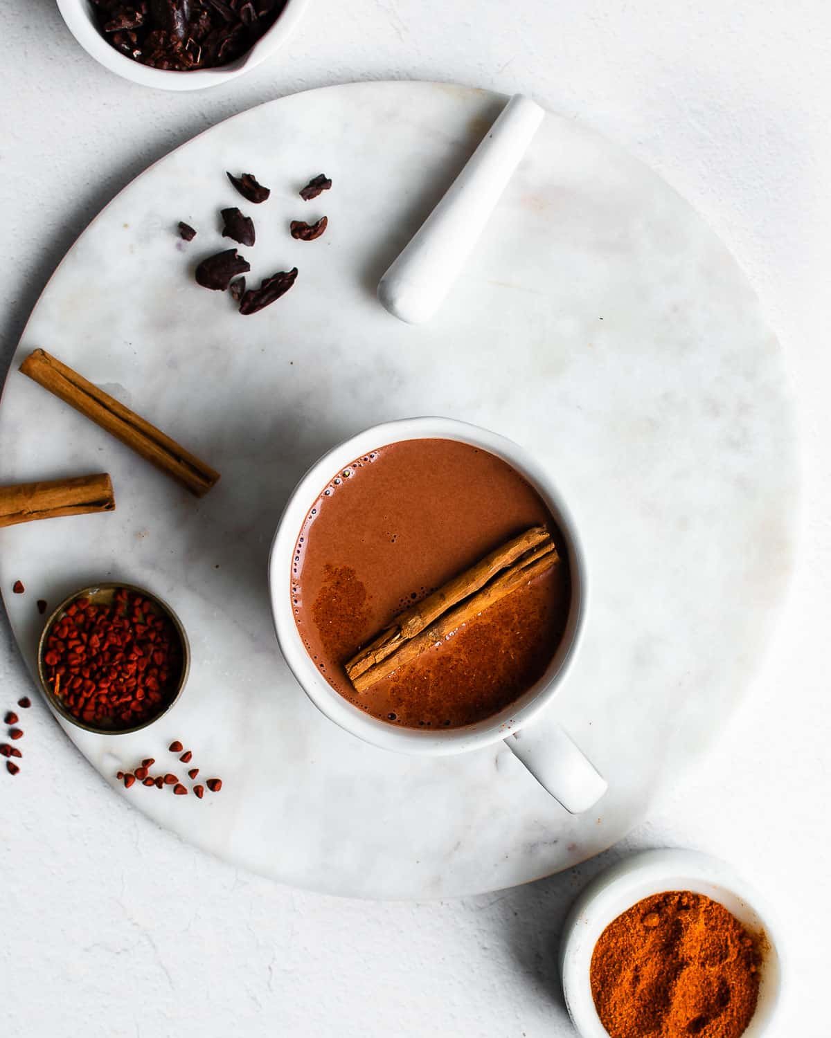 Mayan hot chocolate in a white cup, garnished with cinnamon stick. 