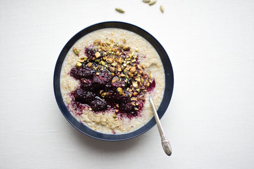 Tender, creamy sprouted quinoa porridge is dressed with a lightly sweetened blackberry sauce spiked with fragrant cardamom.