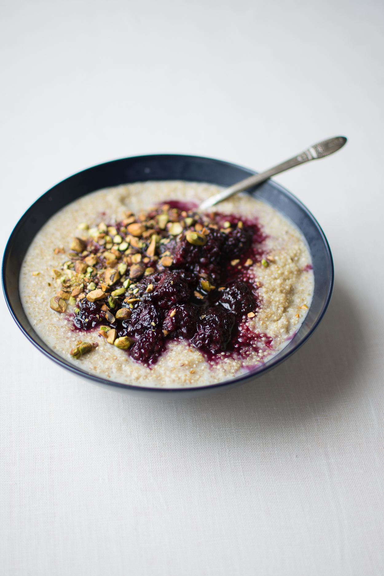 Tender, creamy sprouted quinoa porridge is dressed with a lightly sweetened blackberry sauce spiked with fragrant cardamom.