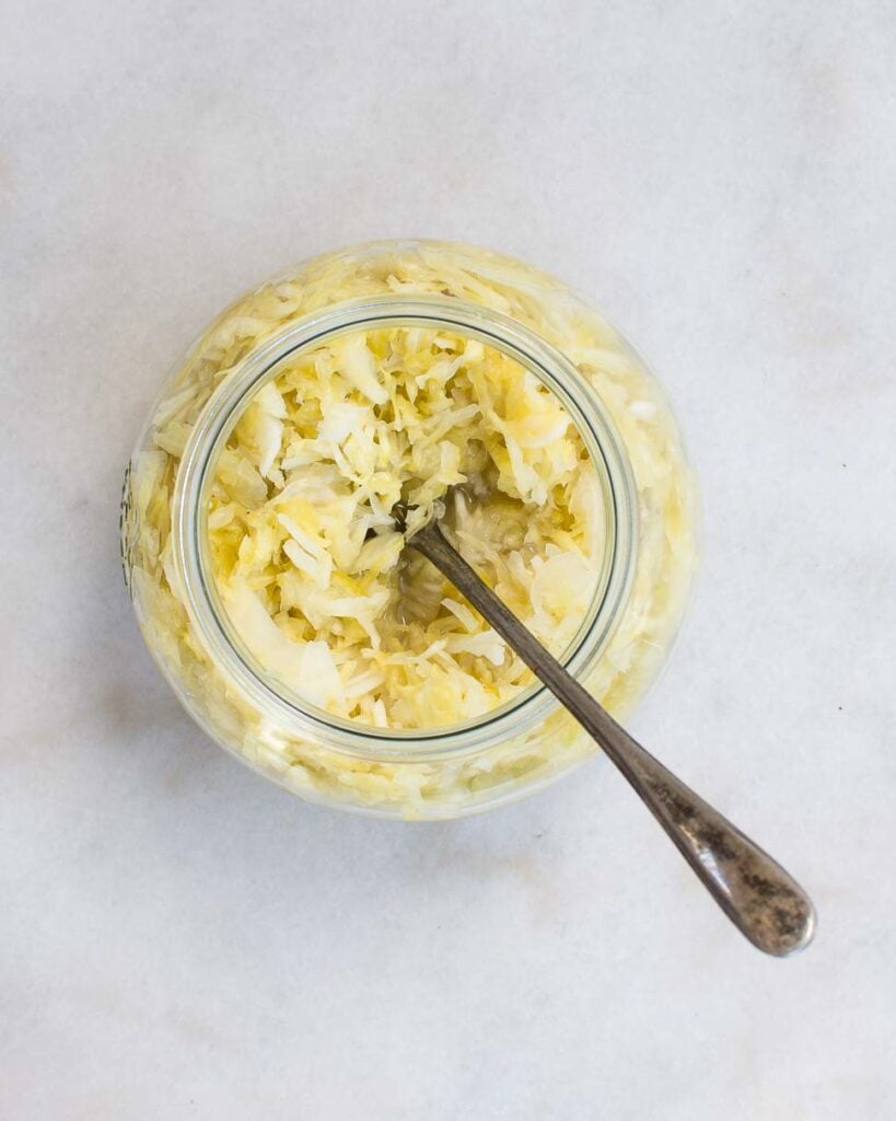 Sauerkraut made from shredded cabbage and sea salt sits in a glass bowl.