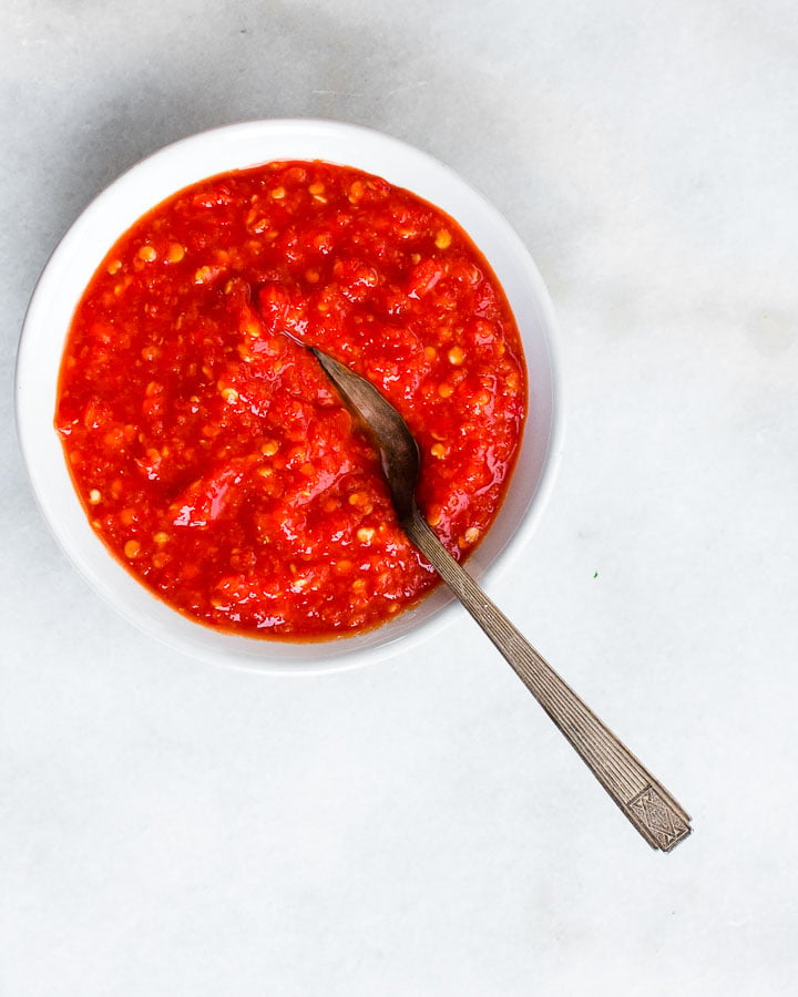 Fermented hot sauce in a bowl with a spoon on a marble surface