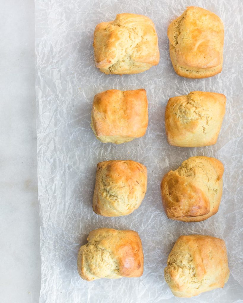 Buttermilk biscuits sitting in two vertical rows on parchment paper.