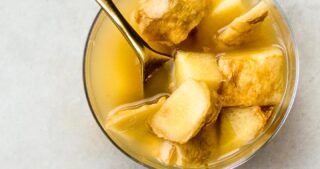 ginger bug in a short glass with a golden spoon on a marble surface