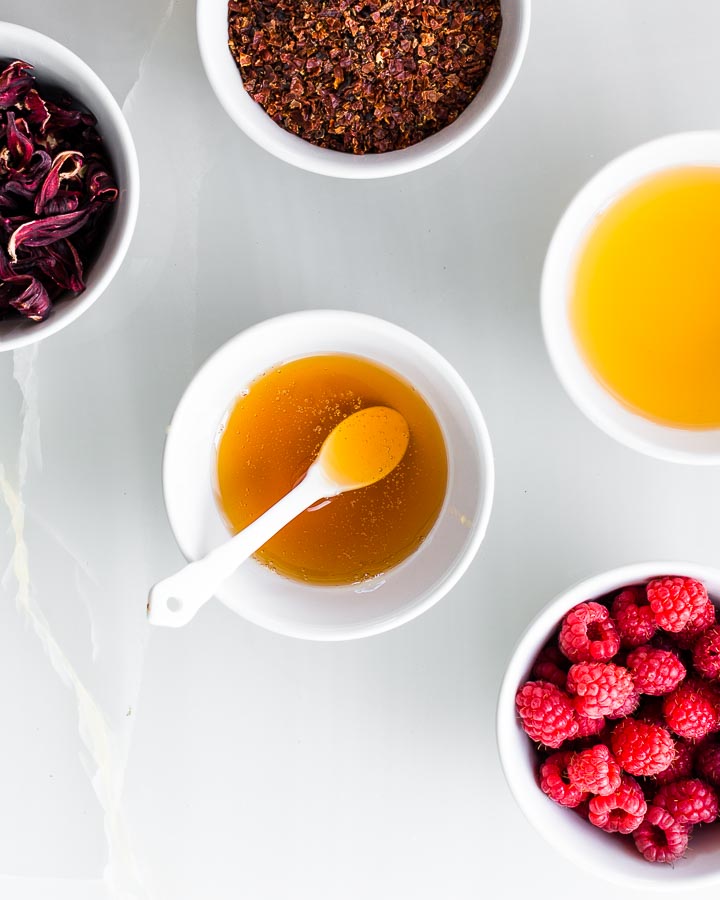 Bowls of raspberries, hibiscus flowers, rosehips, honey and apple cider vinegar.