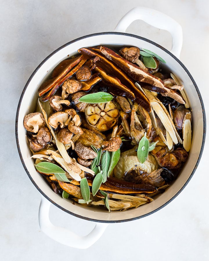 Unstrained medicinal mushroom broth in a white stock pot with sage.