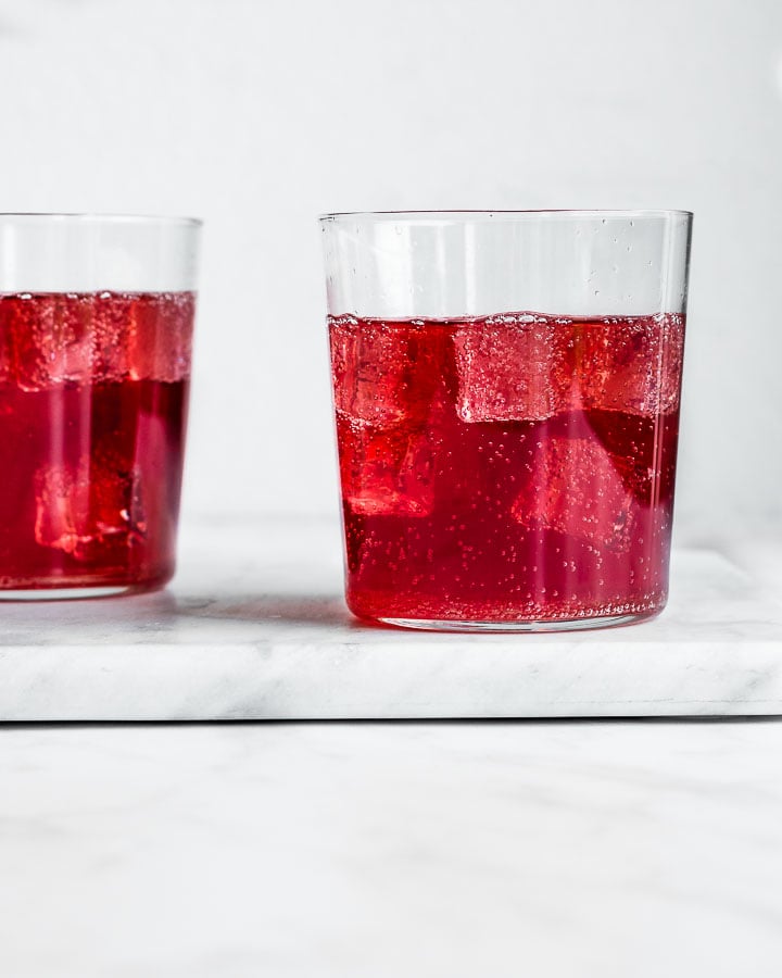 Two glasses of elderberry kombucha served over ice.