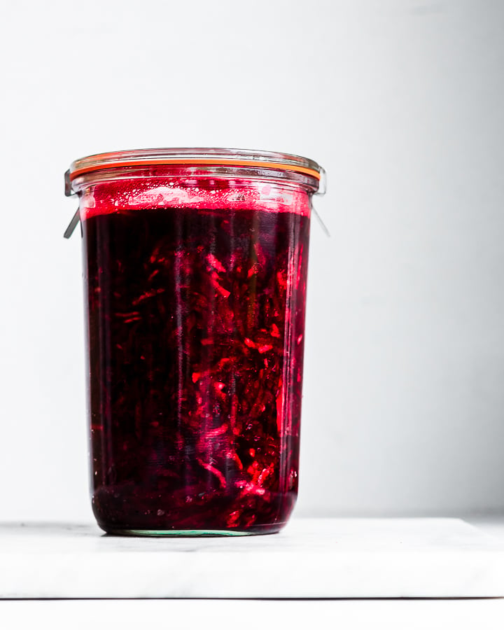 Beetroot relish made with apples and horseradish fermenting in a glass jar.