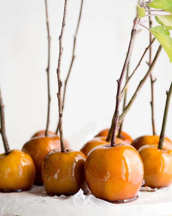 Eight maple-candied apples on a marble stand.