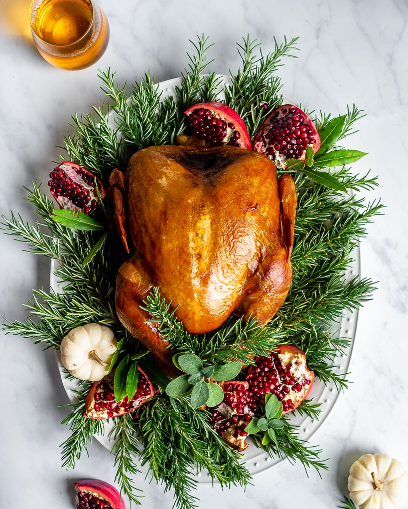 Slow-Roasted Turkey on a platter decorated with rosemary, sage, and pomegranates