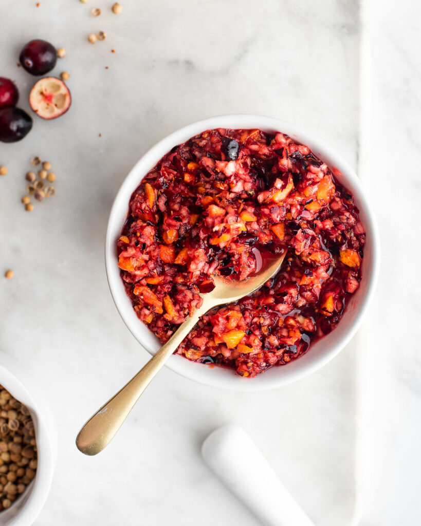 cranberry relish in a white bowl with a brass spoon