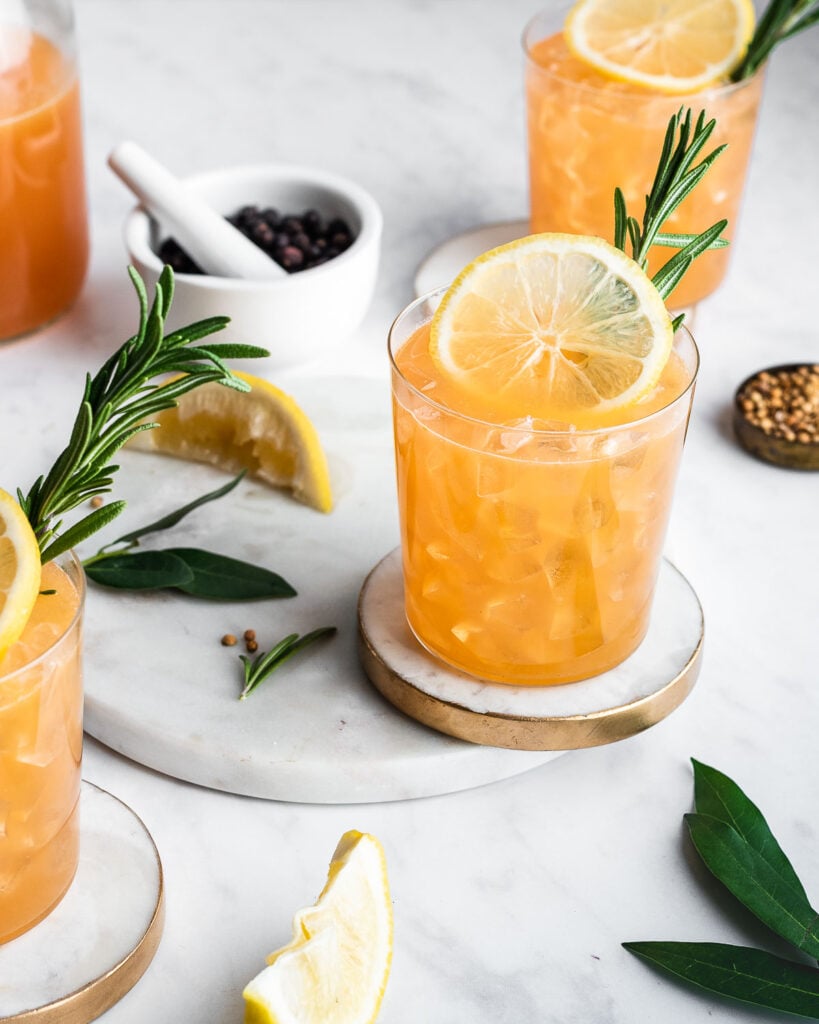 Three glasses of citrus punch garnished with lemon and rosemary.