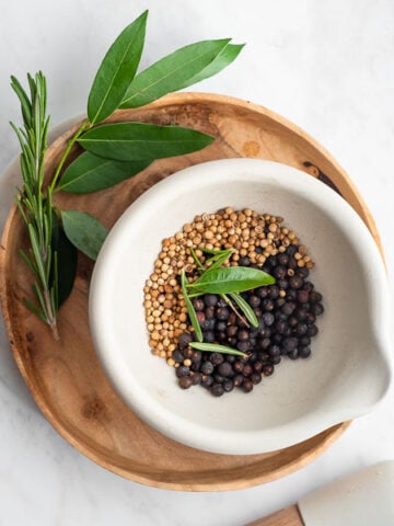 mortar filled with coriander, juniper, bay leaf, and rosemary