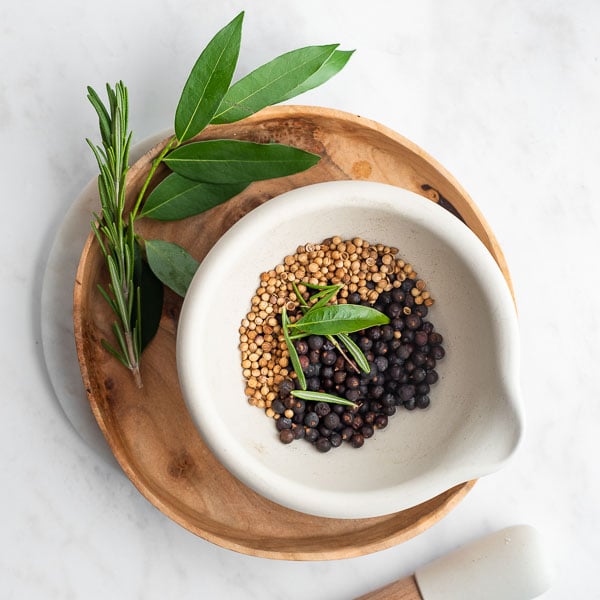 mortar filled with coriander, juniper, bay leaf, and rosemary