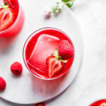 Three glasses of fruit kvass shot from overhead, garnished with ice and strawberries