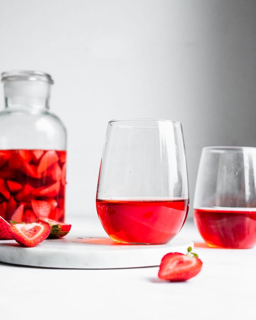 Strawberry wine in two wine glasses, garnished by fresh strawberries.