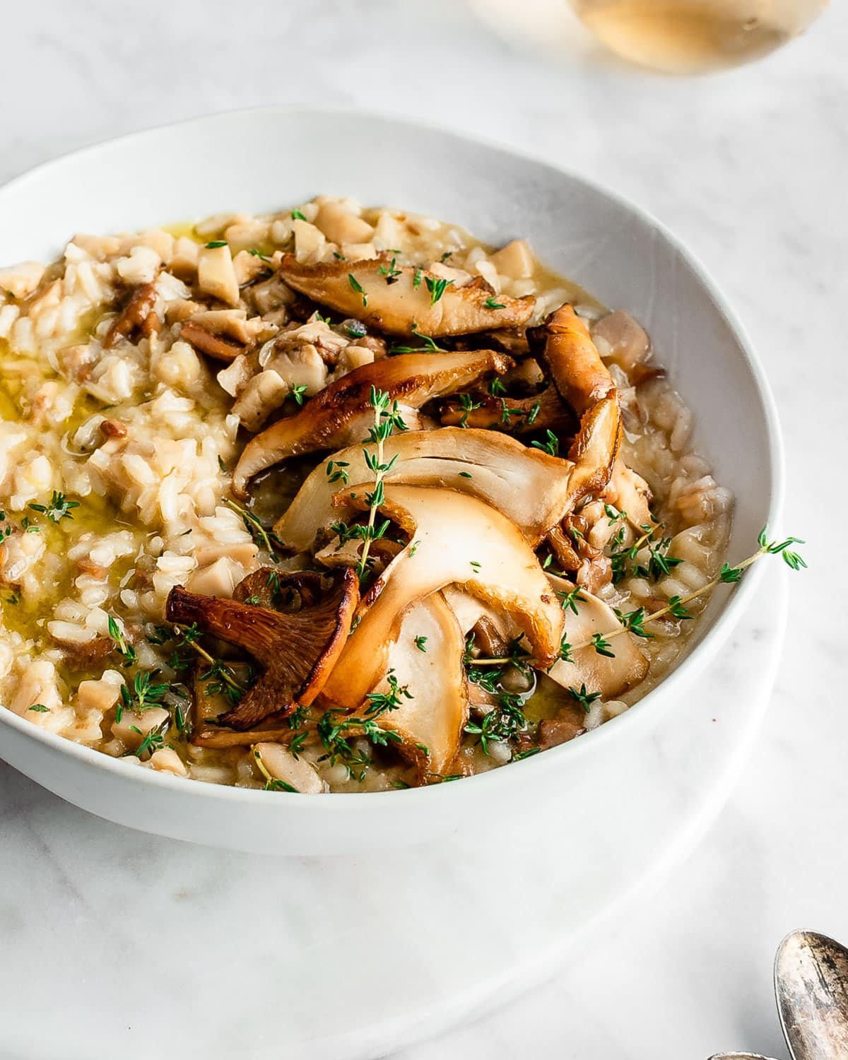 Wild Mushroom Risotto in a white bowl garnished with fresh thyme