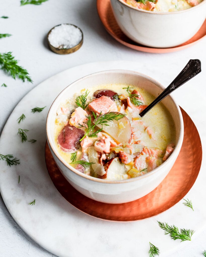 Two bowls of salmon chowder garnished with fresh dill.