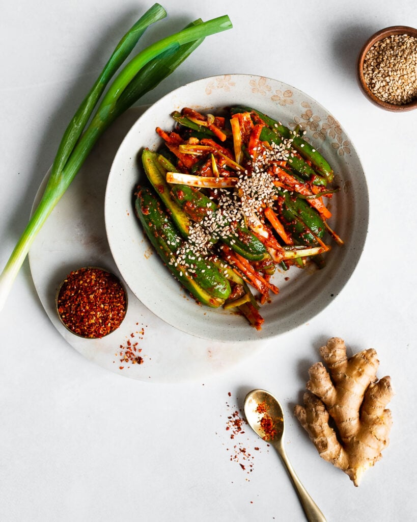 Stuffed cucumber kimchi (oi sobagi) in an earthenware bowl garnished with brown sesame seeds. 