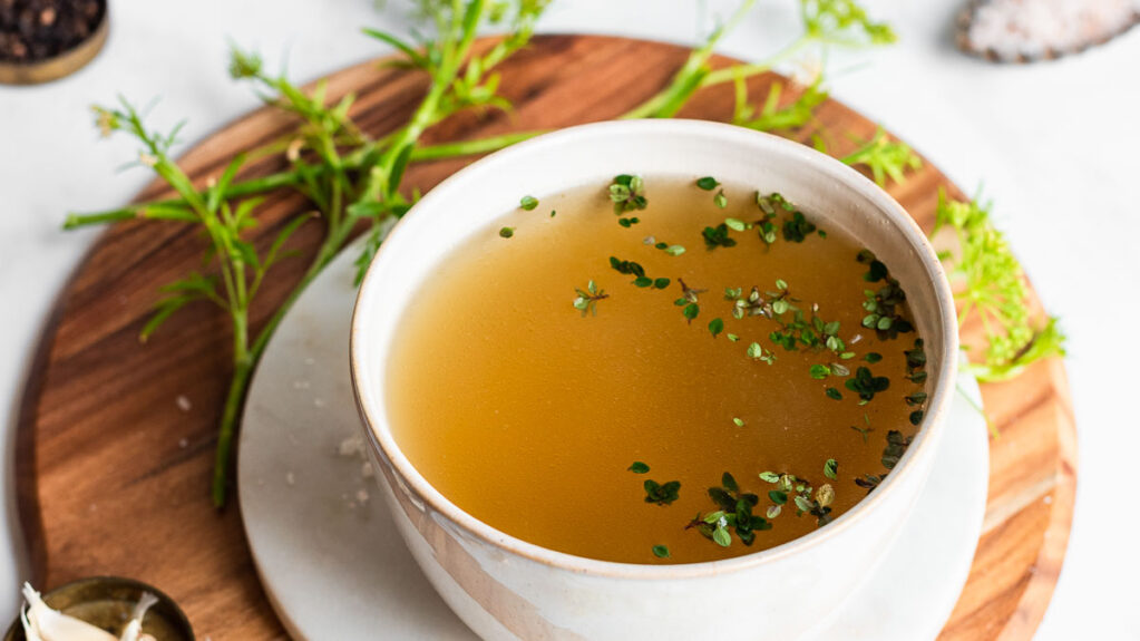 broth in a white bowl garnished with fresh thyme leaves
