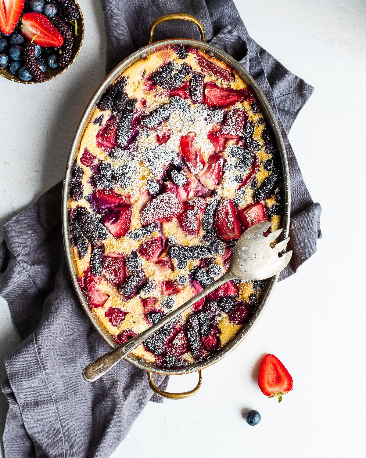 Flaugnarde with blueberries, strawberries, raspberries and mulberries, dusted with powdered sugar