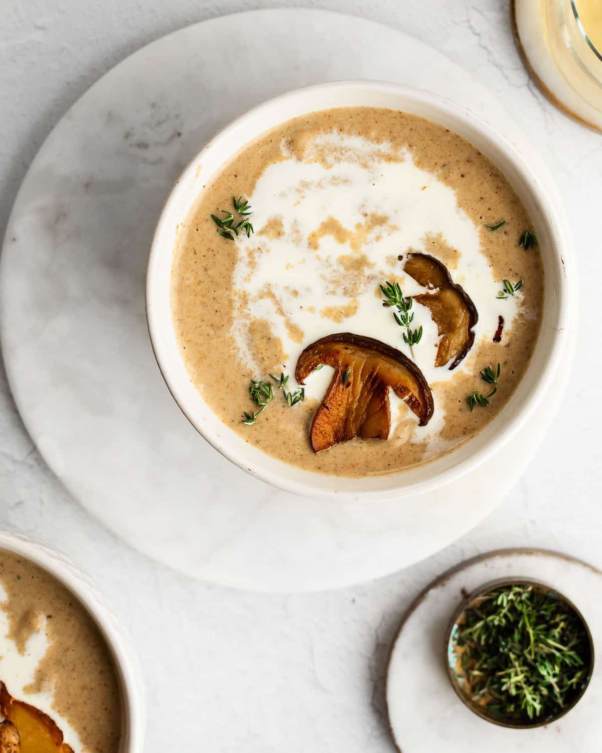 Wild mushroom soup drizzled with cream and sprinkled with fresh thyme in a white bowl