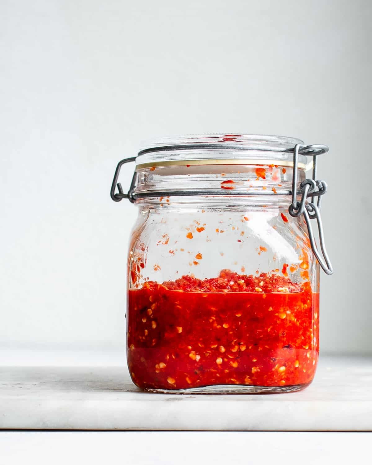 Fermented pepper mash in a glass jar with a clamp lid.