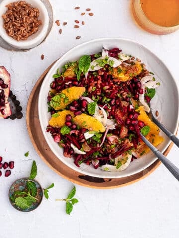 Emmer and beet salad garnished with fennel, oranges and mint in a white bowl