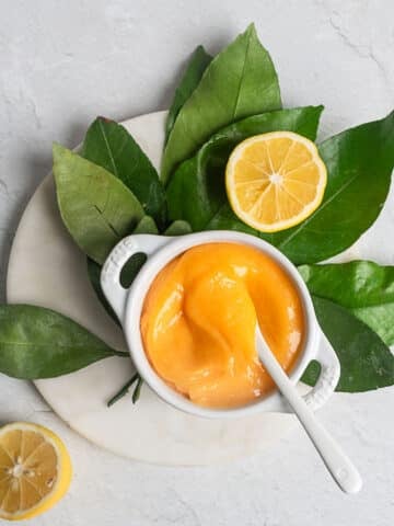 honey lemon curd in a white ramekin on a bed of citrus leaves