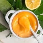 honey lemon curd in a white ramekin on a bed of citrus leaves