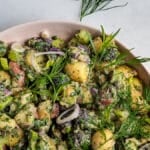 Herbed Potato Salad in a pink bowl garnished with dill and tarragon